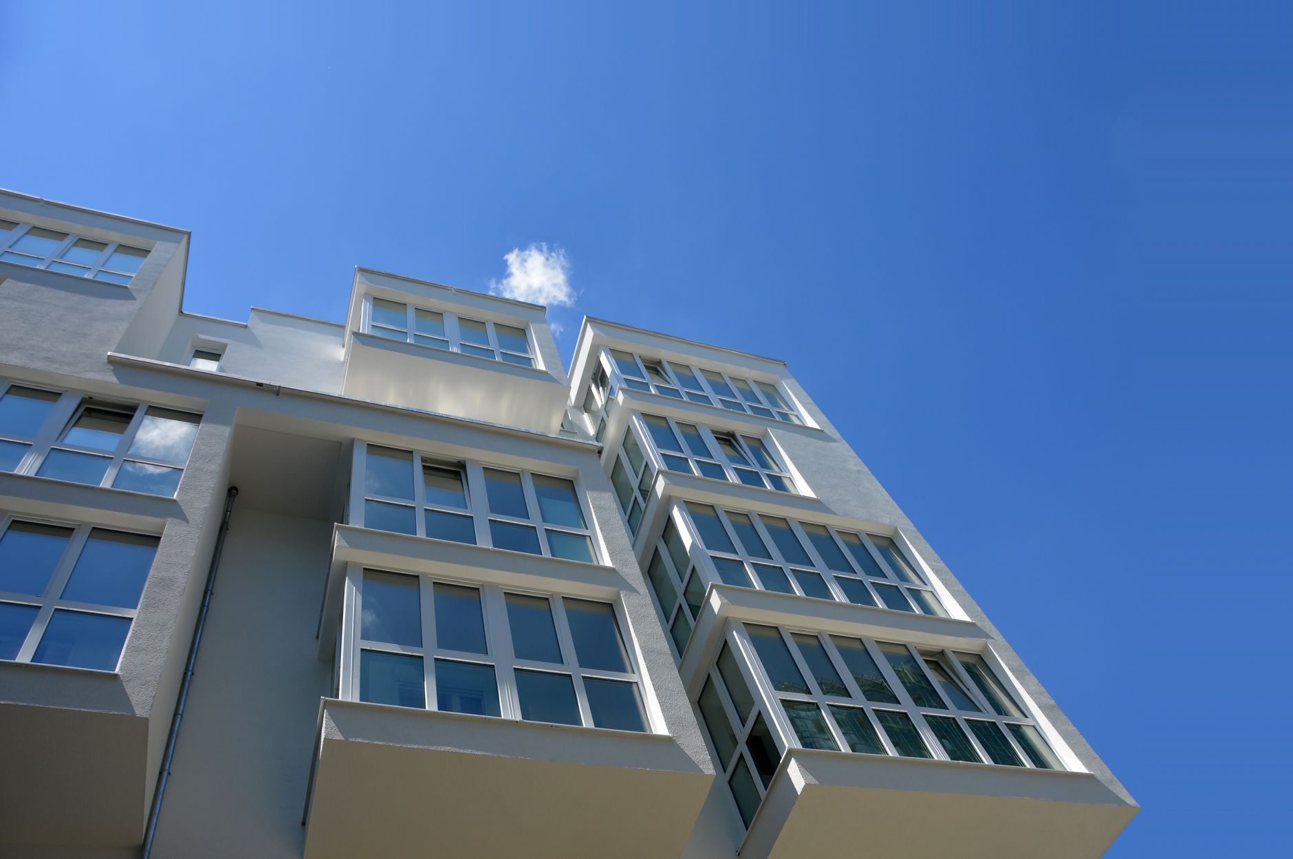 Low angle view of a contemporary apartment building with large glass windows against a clear blue sky in Austin, TX