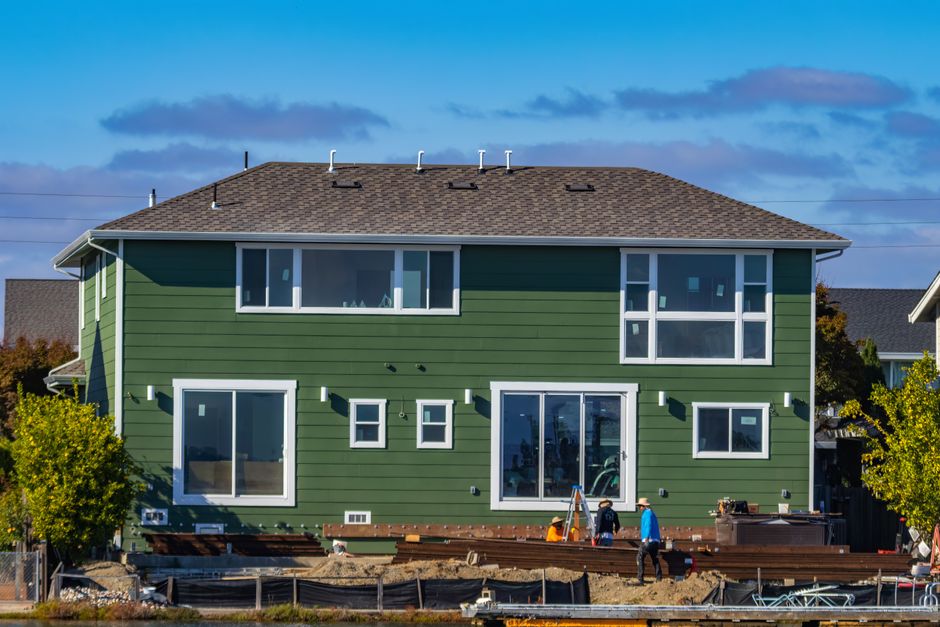 House under construction with workers outside.